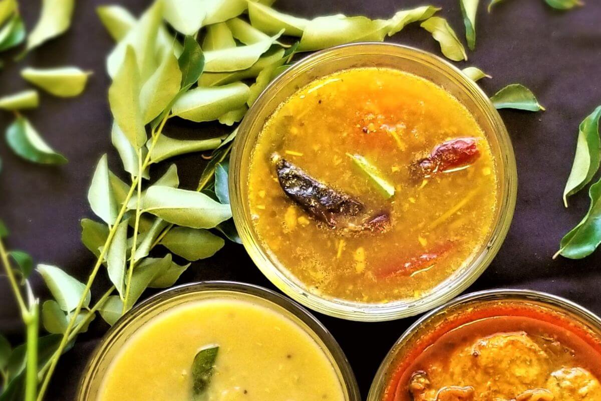 Bowl of rasam with herbs and garlic floating on top.  