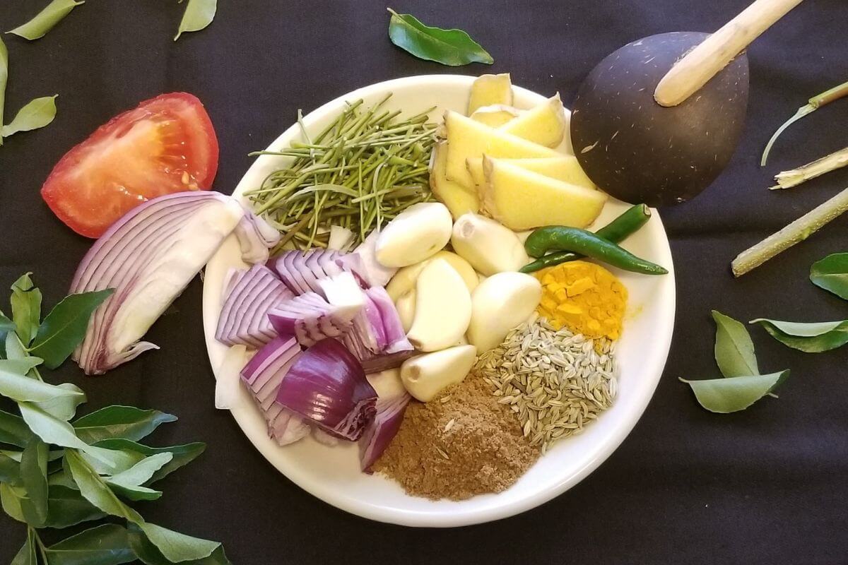 Close-up of ingredints to make rasam showing garlic, herbs, and pepper 