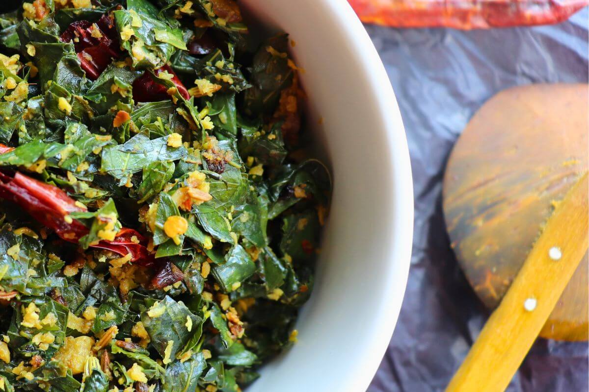 Agathi keerai being stir-fried with onions, chilies, and grated coconut in a pan to present it as a side dish for rice