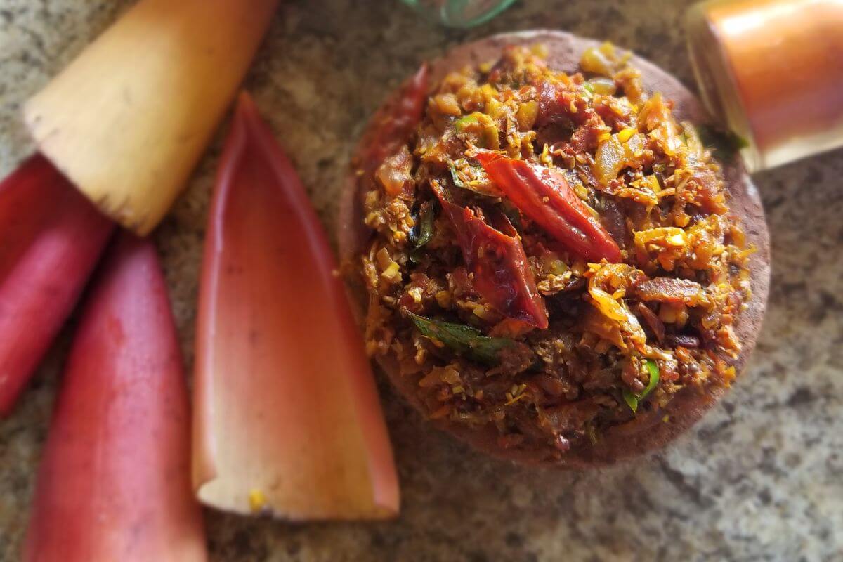 Banana flower being stir-fried with onions, garlic, tomatoes, and spices in a pan.