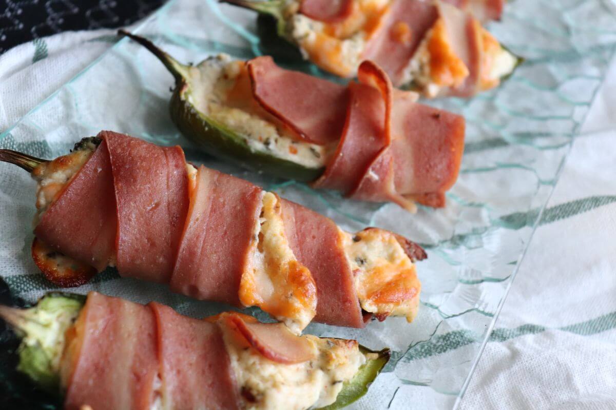 Golden chicken‑wrapped jalapeño poppers arranged closely together, showing melted cheese and crisp edges.