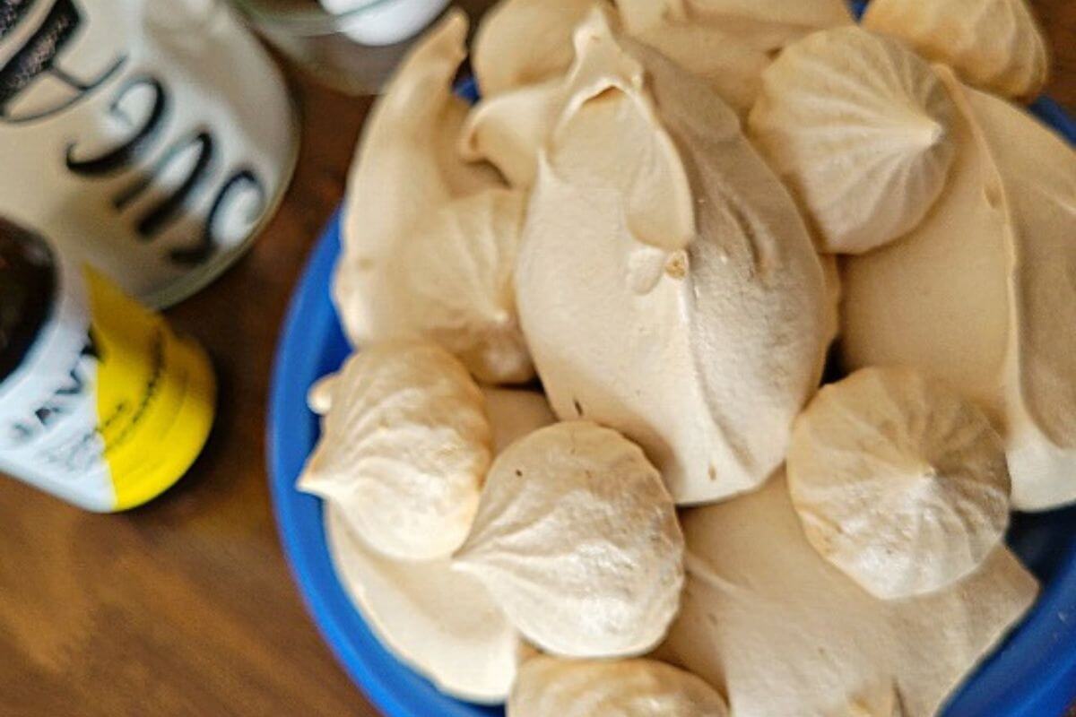 Coffee meringues served beside a cup of hot coffee.