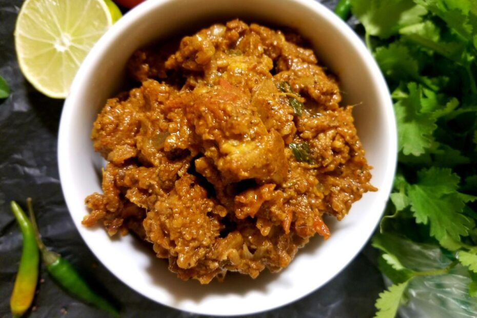 Dry‑style meat curry served in a bowl with thick, spice‑coated pieces of meat.