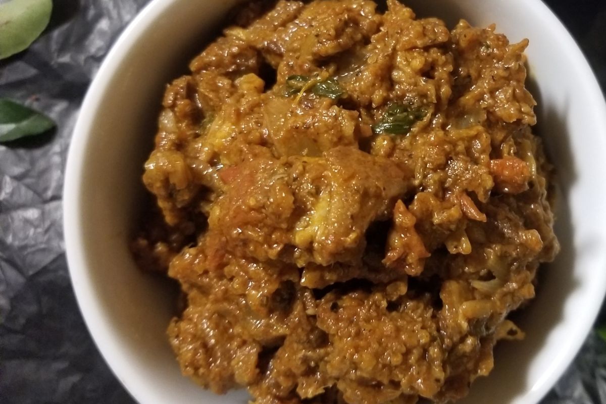 Close‑up of dry‑style meat curry with visible spices and caramelized masala.  