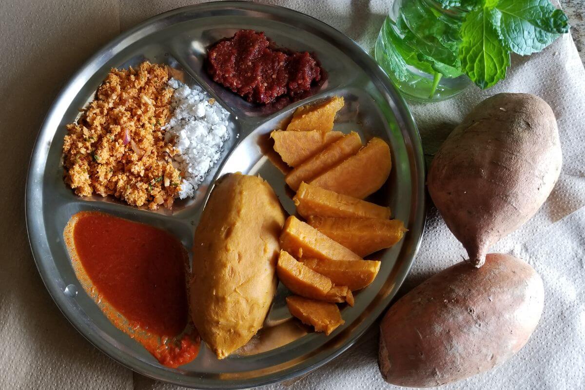 Boiled sweet potatoes served on a plate with chili sauce.