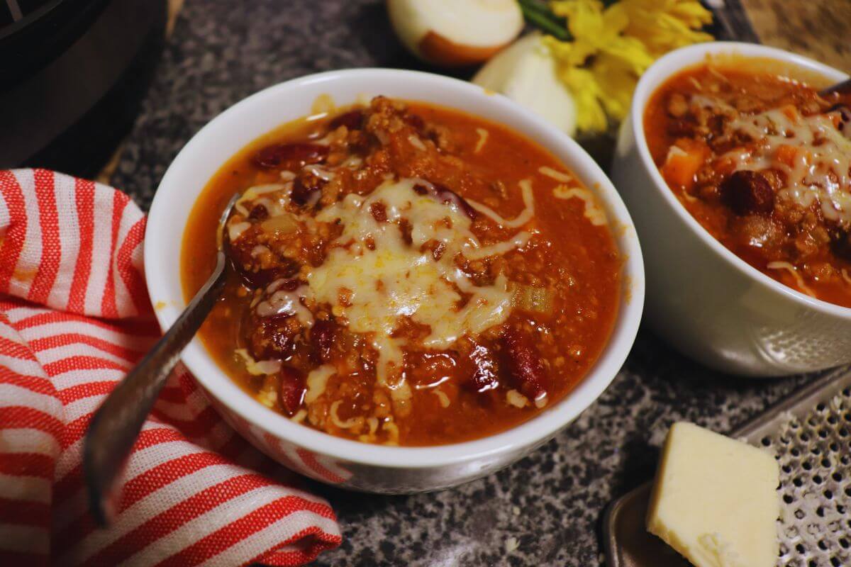 Bowl of Power Pressure Cooker chili topped with cheese and herbs.