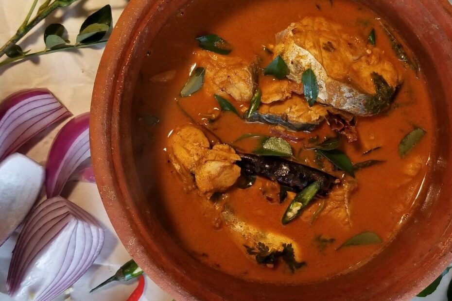Close‑up of fish curry showing tender fish pieces coated in rich red gravy.