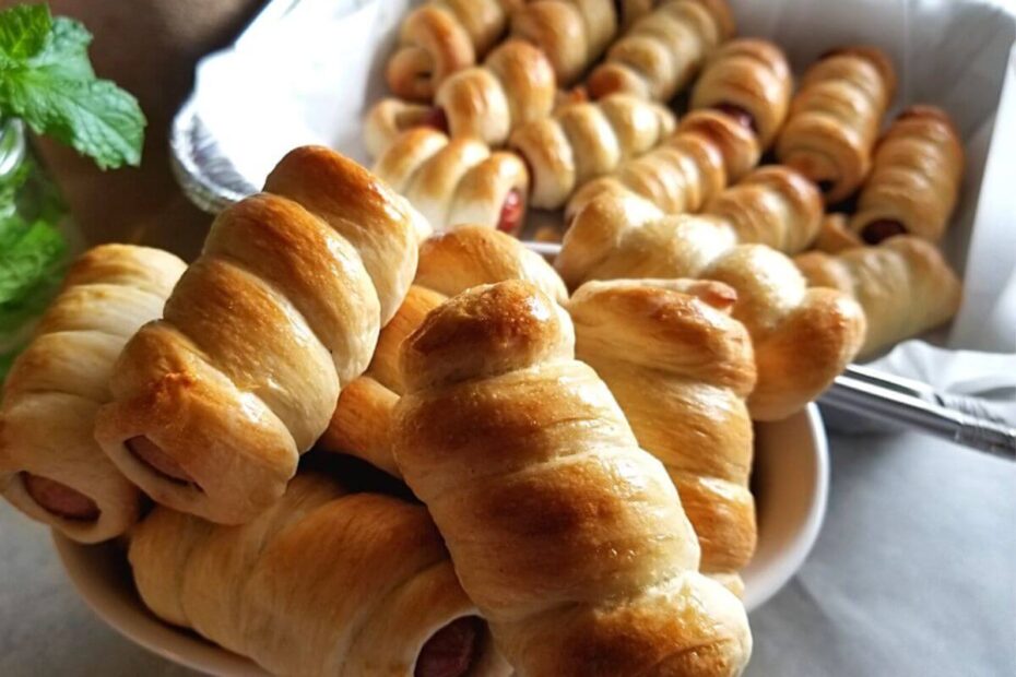 Freshly baked hotdog buns arranged on a plate, golden and ready to serve.