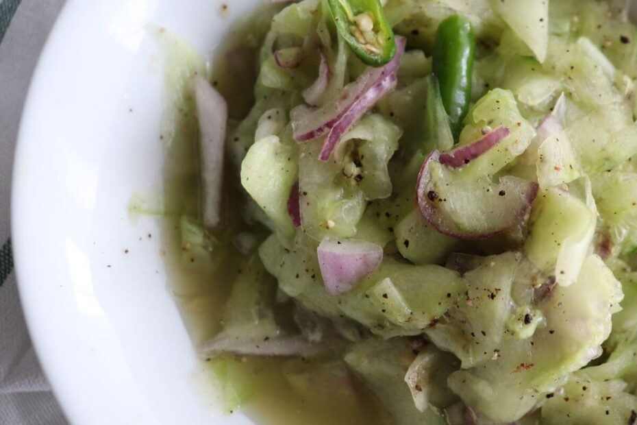 Close‑up of Sri Lankan cucumber sambal served in a white bowl, showing thin cucumber ribbons, onions, and green chilies.