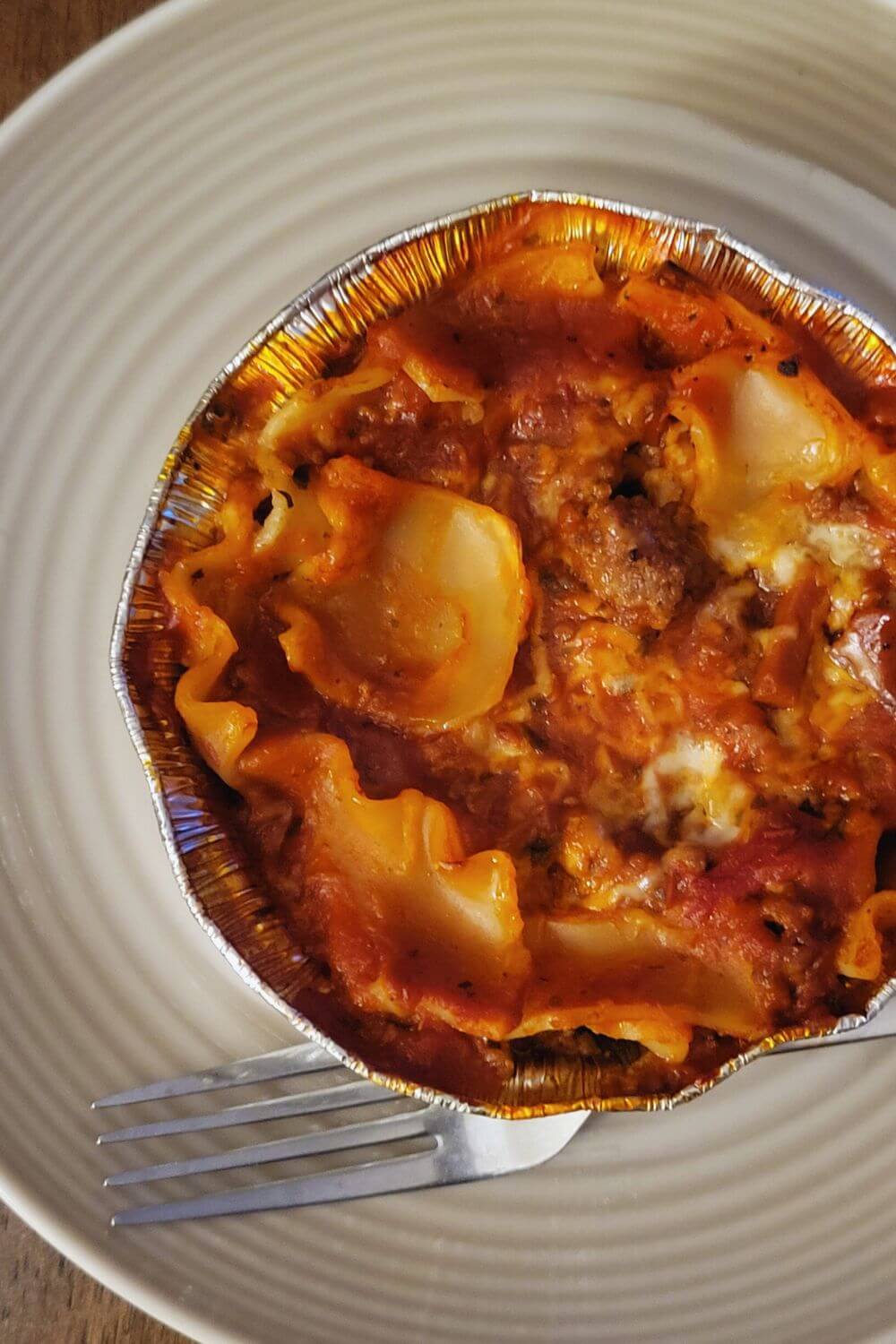pin image featuring a closeup of layered beef lasagna on a oven-safe bowl