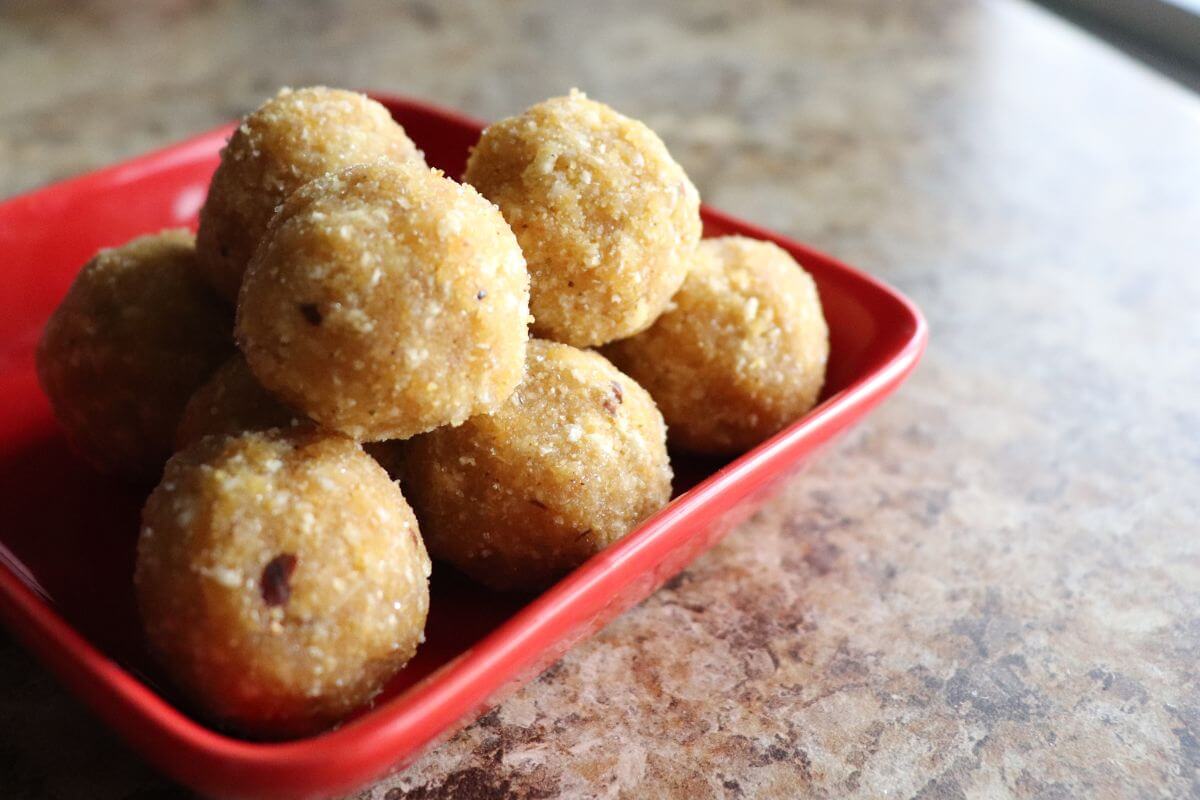 Close‑up of Samaposha energy balls stacked in a red plate, showing their soft, no‑bake texture.