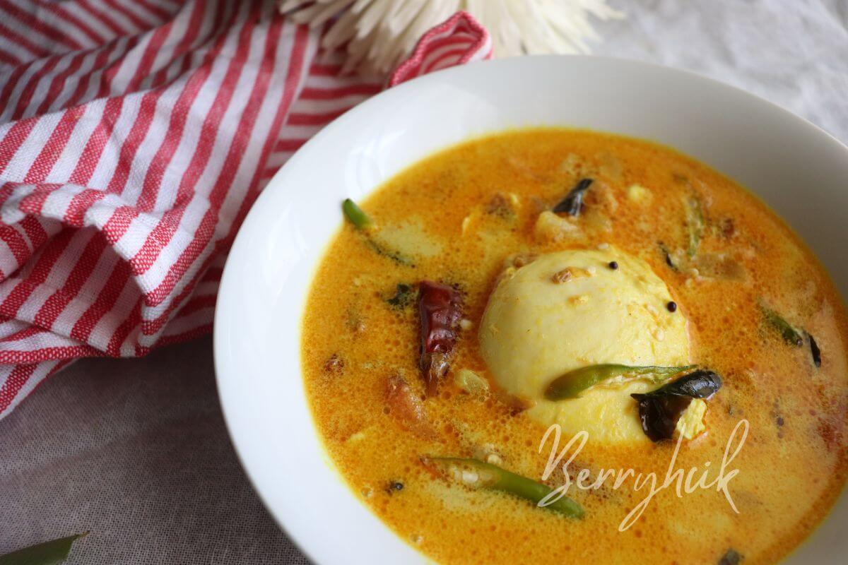 Overhead view of Sri Lankan poached egg curry with onions, tomatoes, and coconut milk, light and nourishing egg dish for string hoppers.