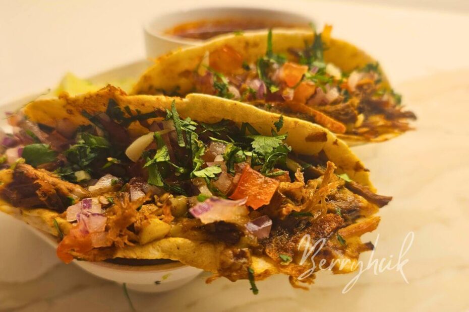Close‑up of birria tacos with juicy shredded beef and melted cheese, topped with cilantro and onion.