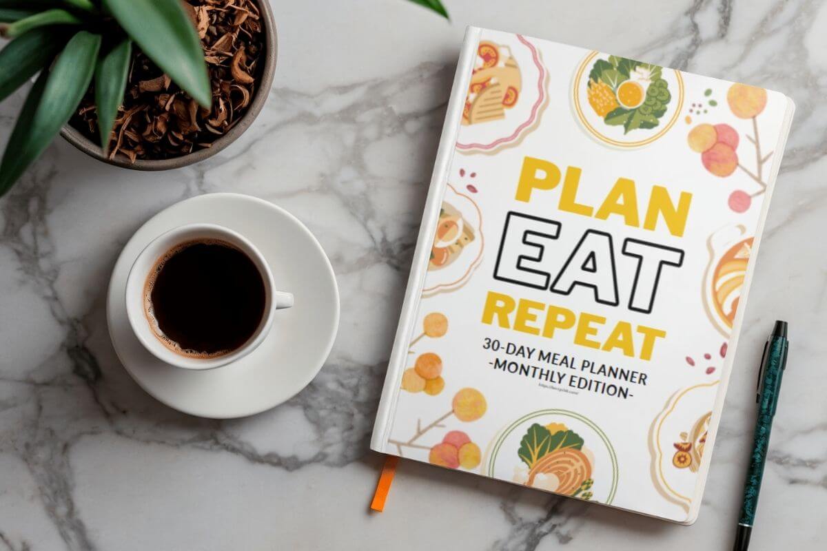 Meal planner on a kitchen counter with a cup of coffee and a pen beside it.