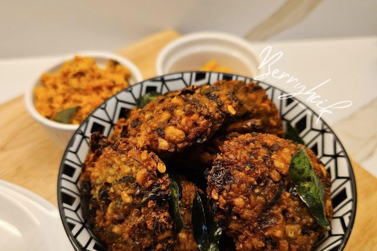 Sri Lankan parippu vada served in a bowl with curry leaves and a small dish of dipping sauce.