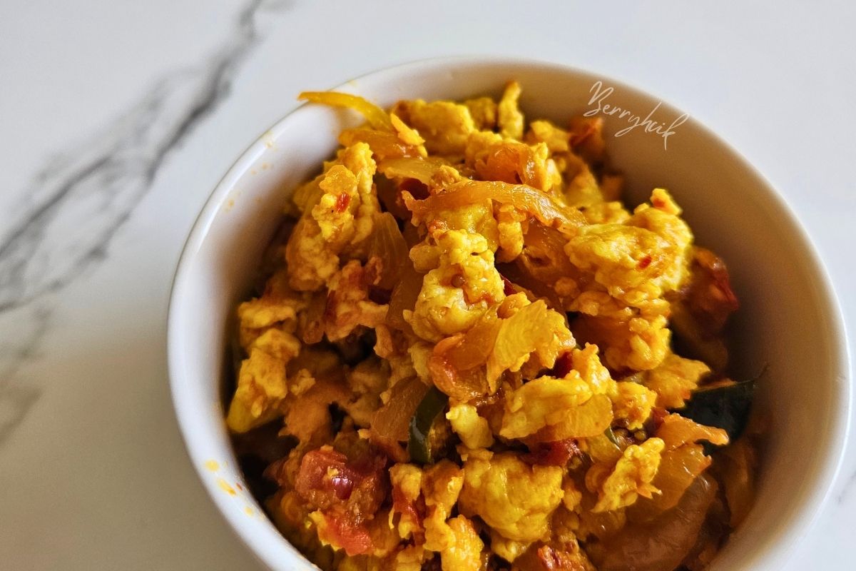 Sri Lankan scrambled egg sambal in a white bowl with onions, tomatoes, and spices.