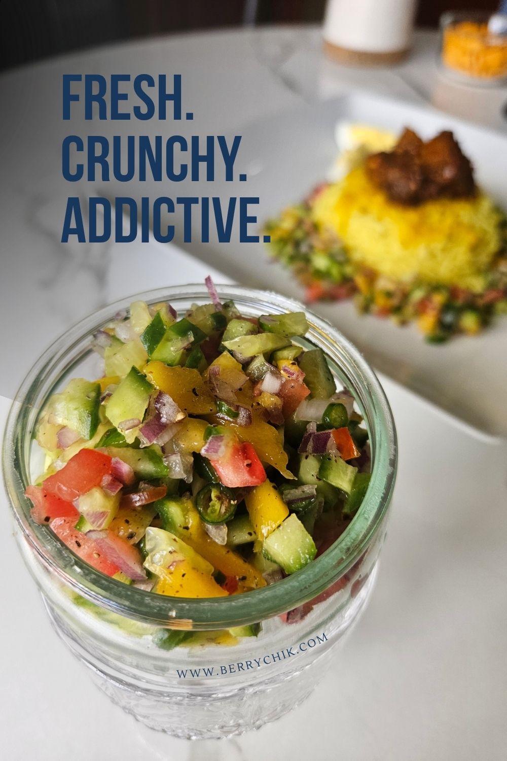 Glass jar filled with colorful cucumber pineapple salad in front of a Sri Lankan rice plate.
