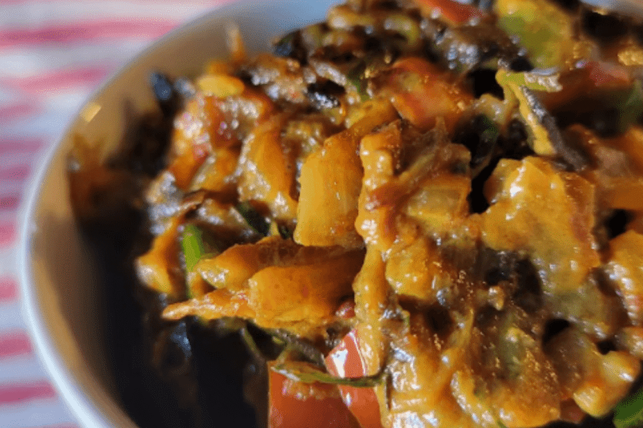 Bowl of creamy Sri Lankan eggplant curry with coconut milk, garnished with curry leaves and red chilies.