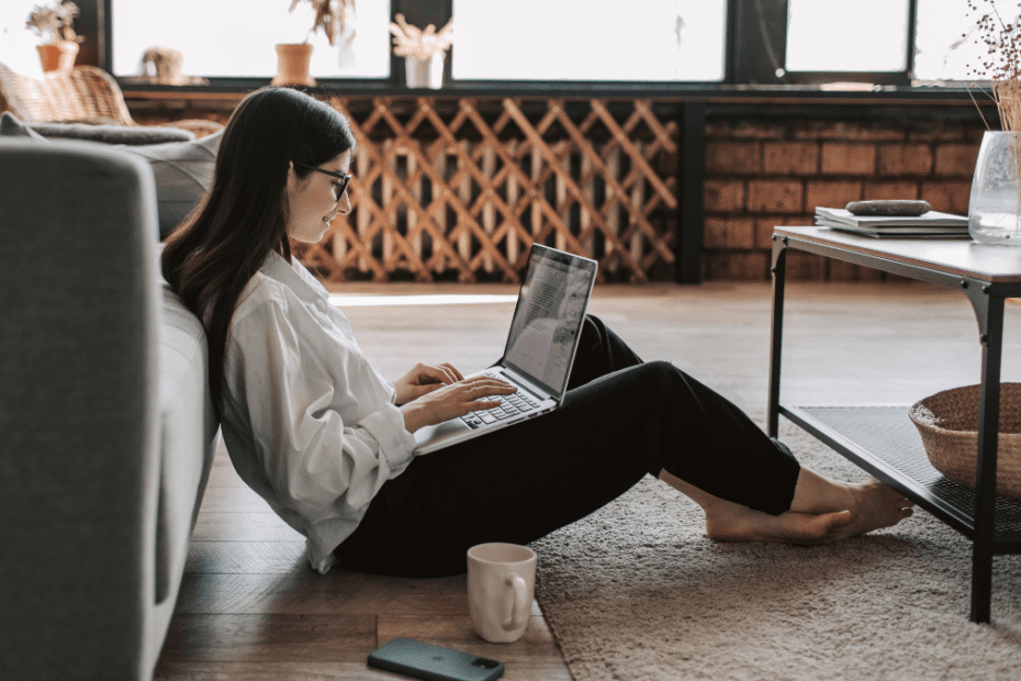 Person sitting on the floor with a laptop, drafting a recipe blog post in a cozy living room