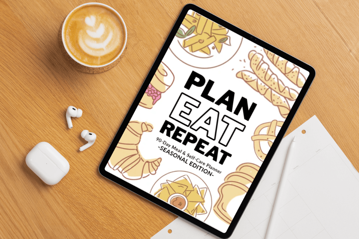 a table displaying a meal planner laying on a table top with a cup of coffee and other things scattered