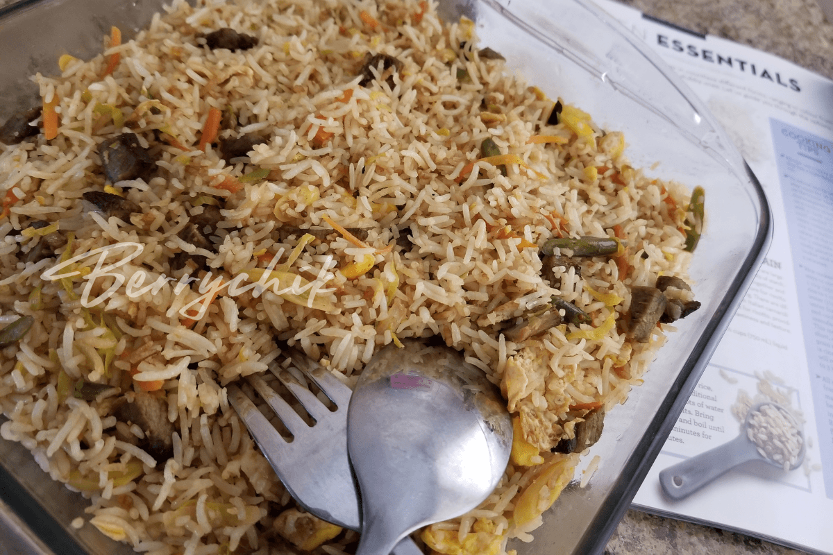 Serving spoon resting in a dish of homemade fried rice with chicken, vegetables, and egg